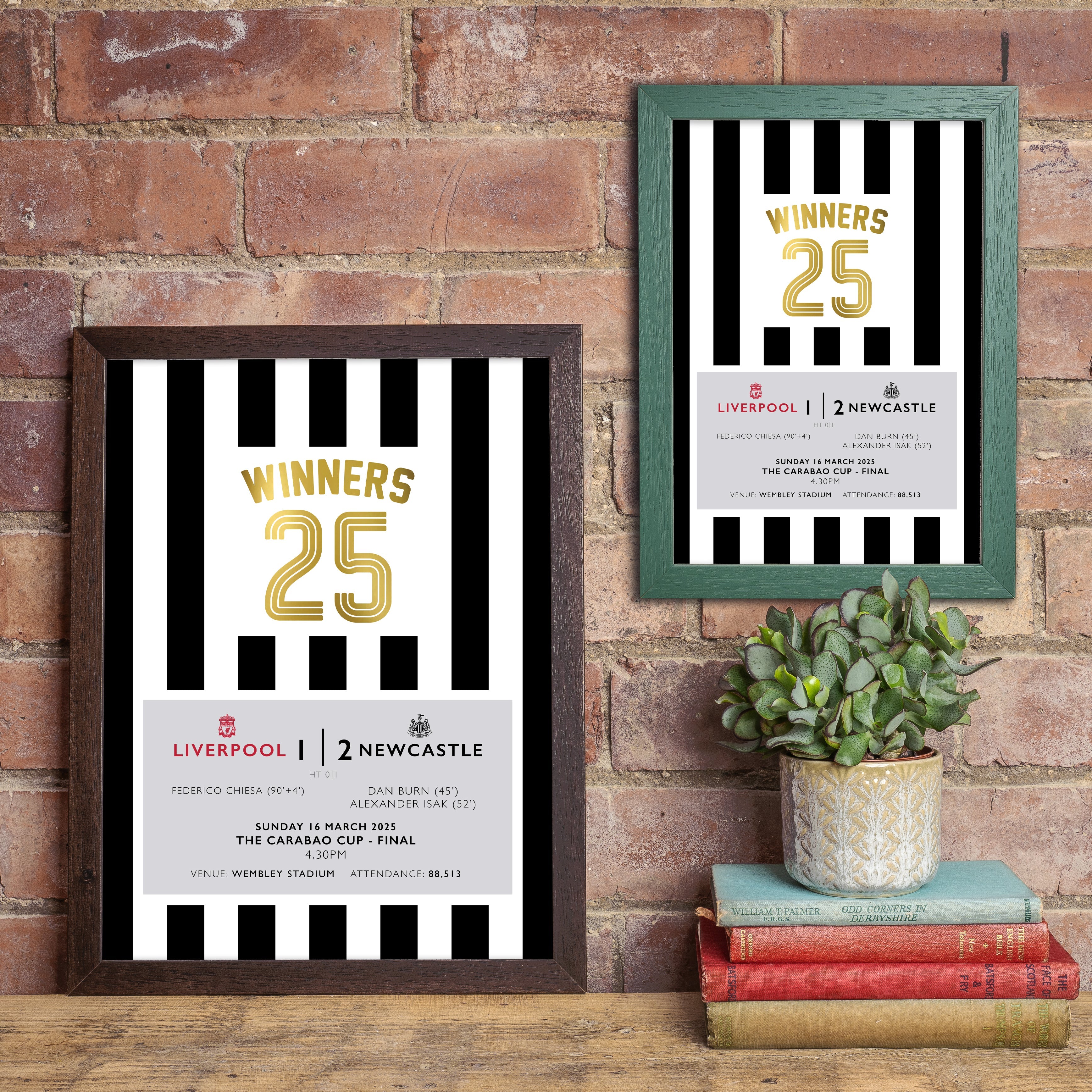 Two framed black-and-white striped prints celebrating Newcastle’s 2–1 Carabao Cup Final win over Liverpool, with “Winners 25” in gold lettering, displayed on a brick wall above books and a plant.
