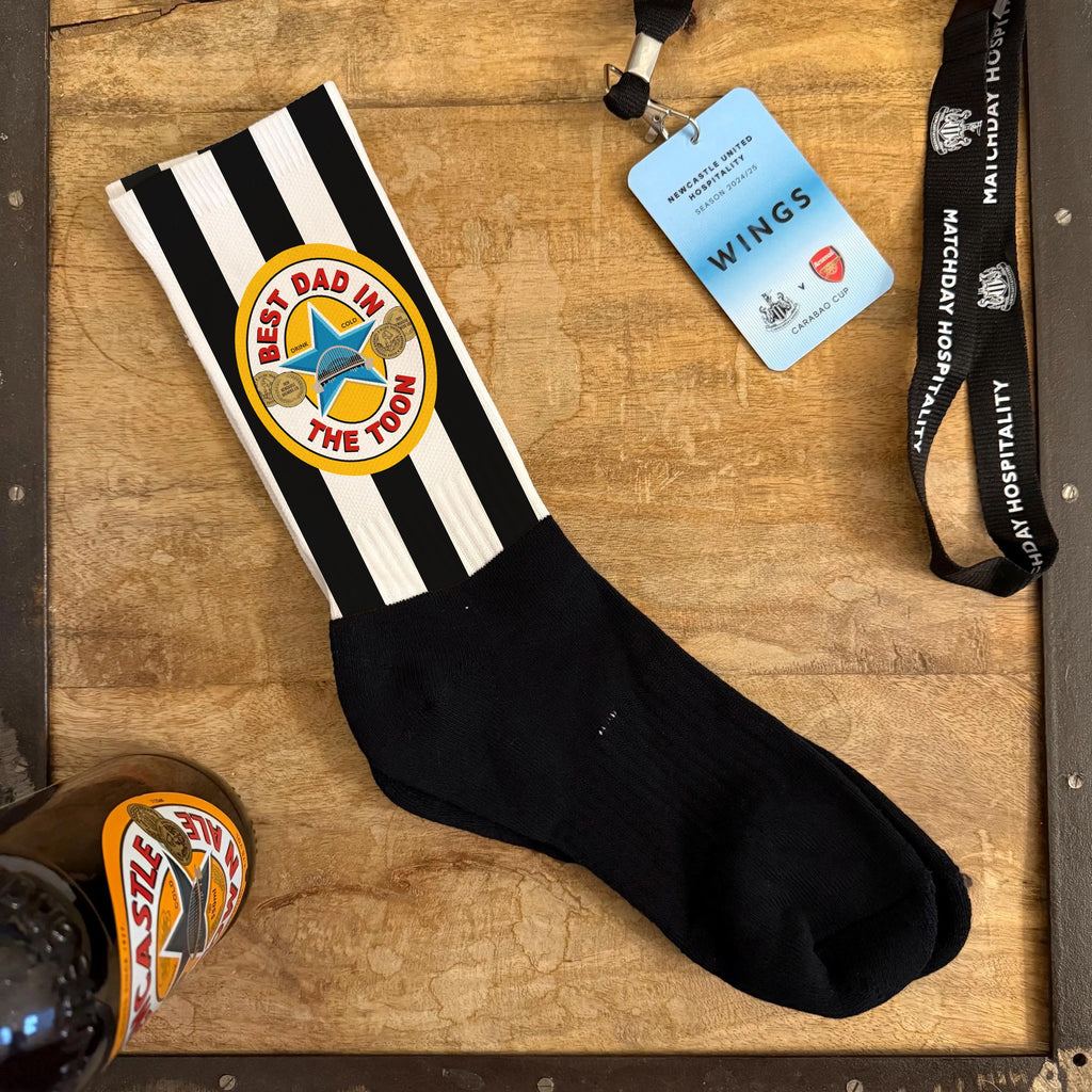 Black and white striped sock with a logo on a wooden surface, next to a lanyard and badge.
