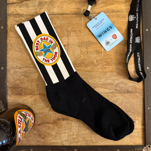 Black and white striped sock with a logo on a wooden surface, next to a lanyard and badge.